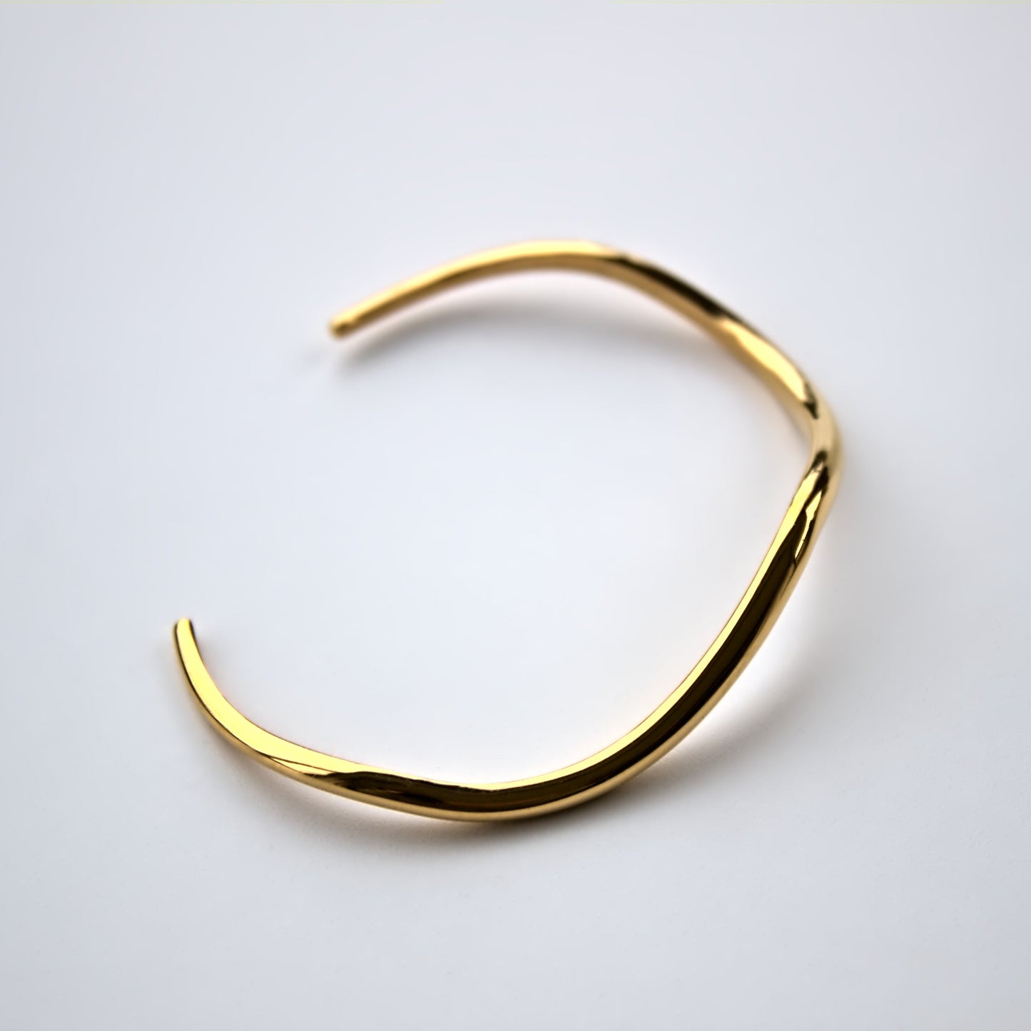 Side profile of V shaped cuff bangle on white surface.
