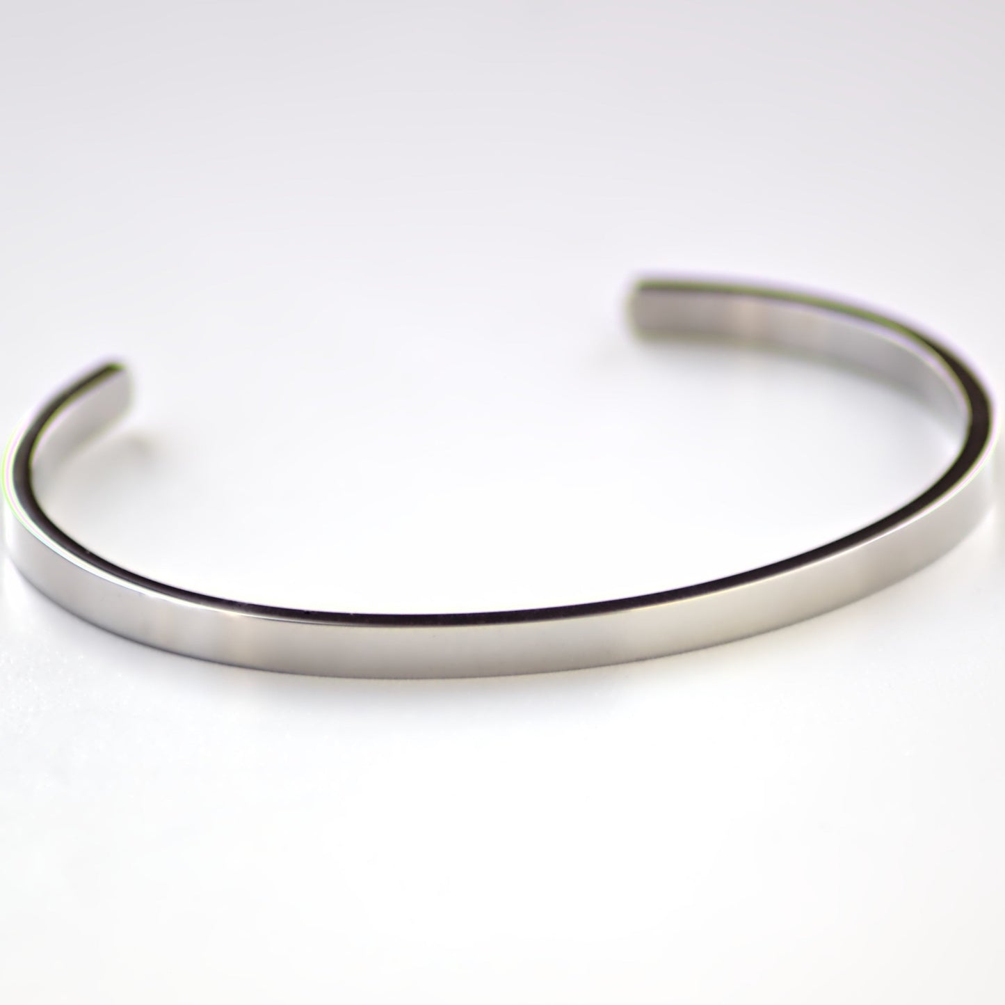 Silver cuff bangle laying flat on a white surface, with the front of the bangle in focus