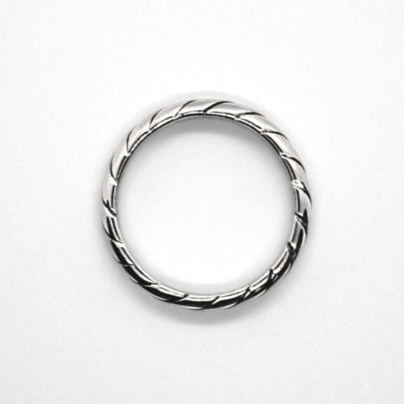 Simple silver circle ring with striped engraved pattern all around. Sitting face down on white background and top-down view.