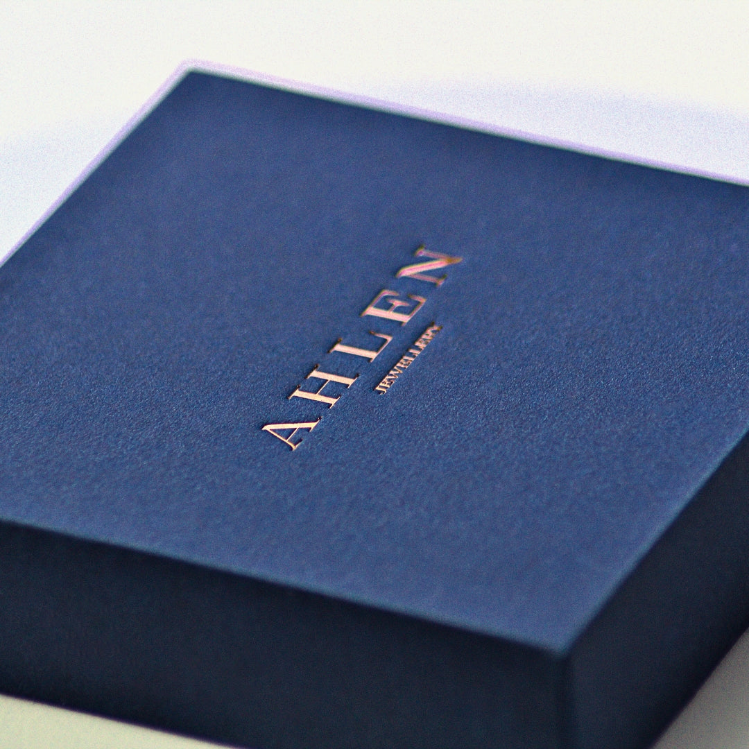 Ahlen Jewellery branded square blue gift box, featuring Ahlen Jewellery text written in the middle in debossed style. Slight angled view of box. 