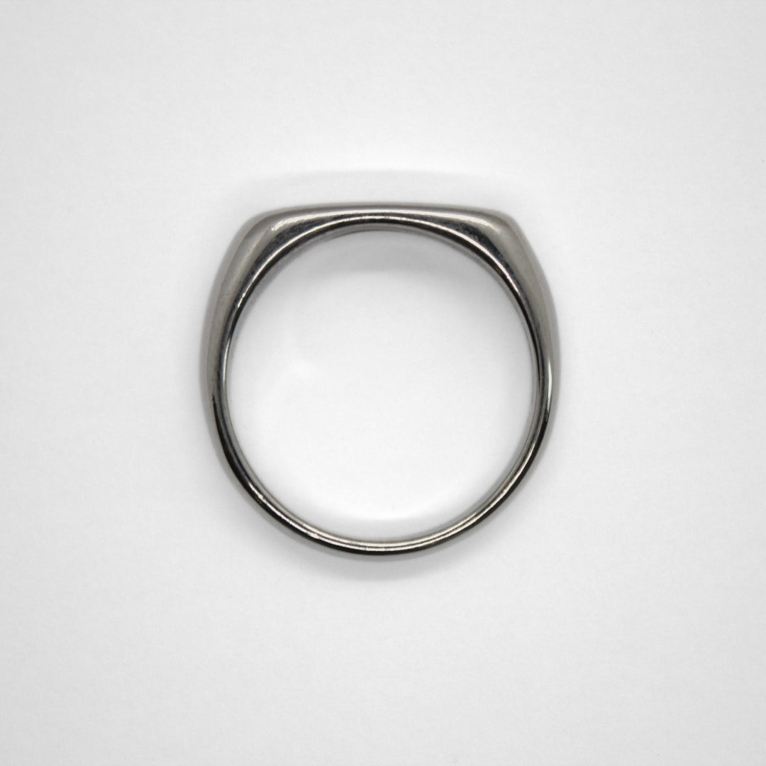 Flat edge silver signet ring facing upwards, flat on white surface.